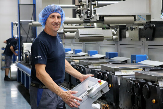 Un employé fait fonctionner une machine à imprimer.