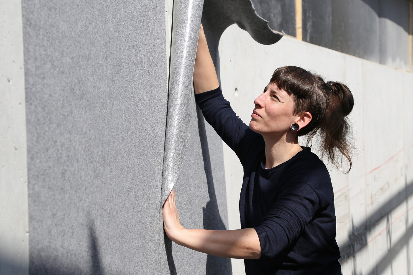 Une peintre pose le non-tissé de protection autocollant Allfelt 1130 sur un mur
