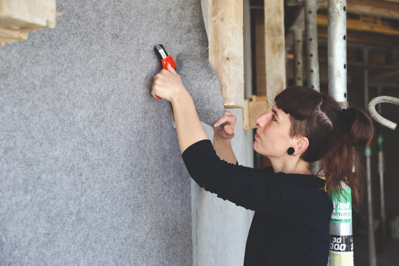 Une peintre pose le non-tissé de protection autocollant Allfelt 1130 sur un mur