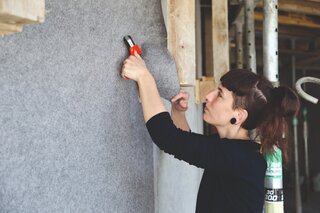 Une peintre pose le non-tissé de protection autocollant Allfelt 1130 sur un mur