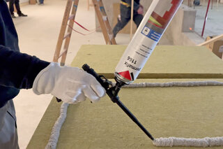 Un ouvrier injecte de la mousse adhésive Permafix 1166 sur un panneau isolant.