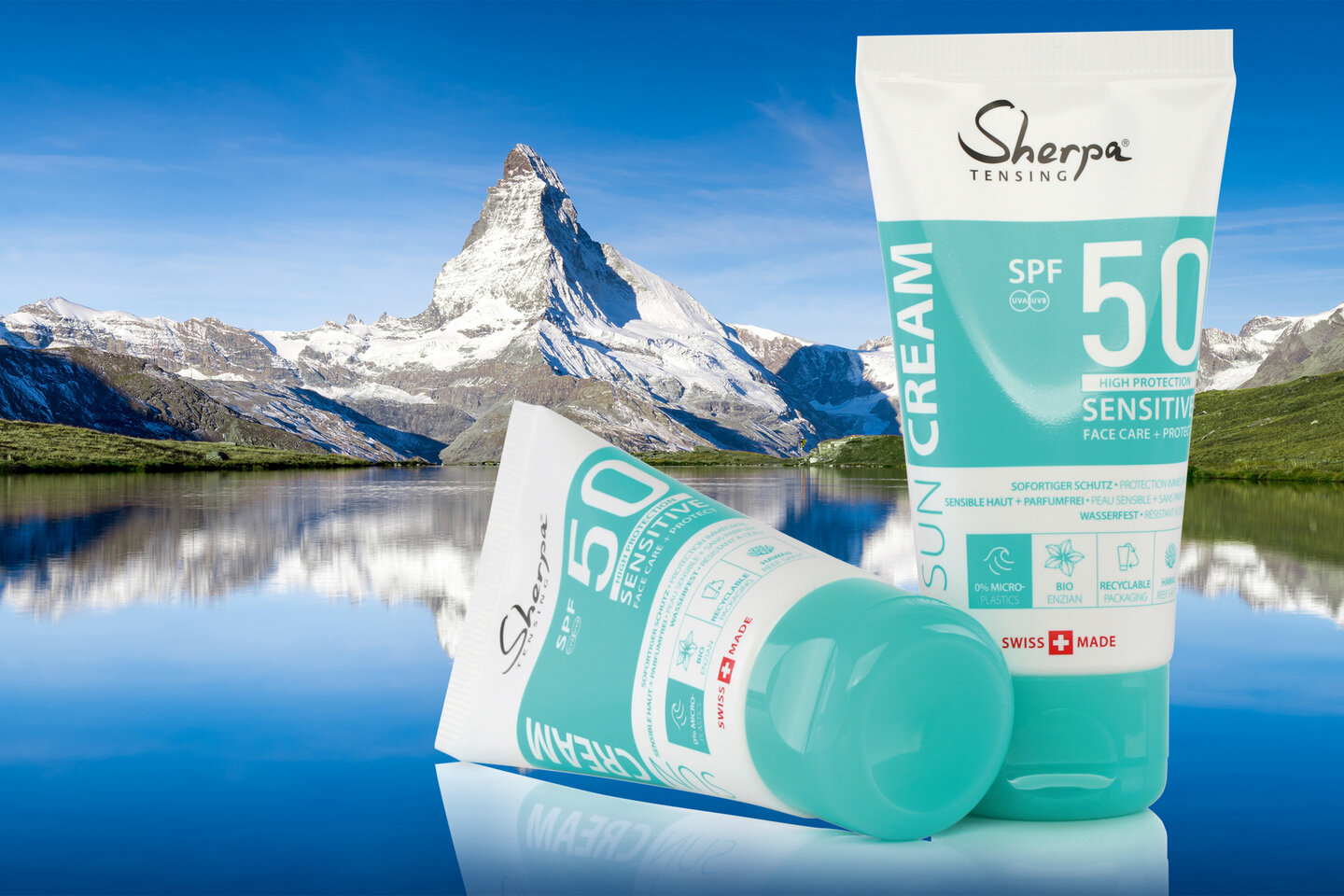 En arrière-plan, le Cervin et un lac, et au premier plan, deux tubes laminés contenant de la crème solaire Sherpa.