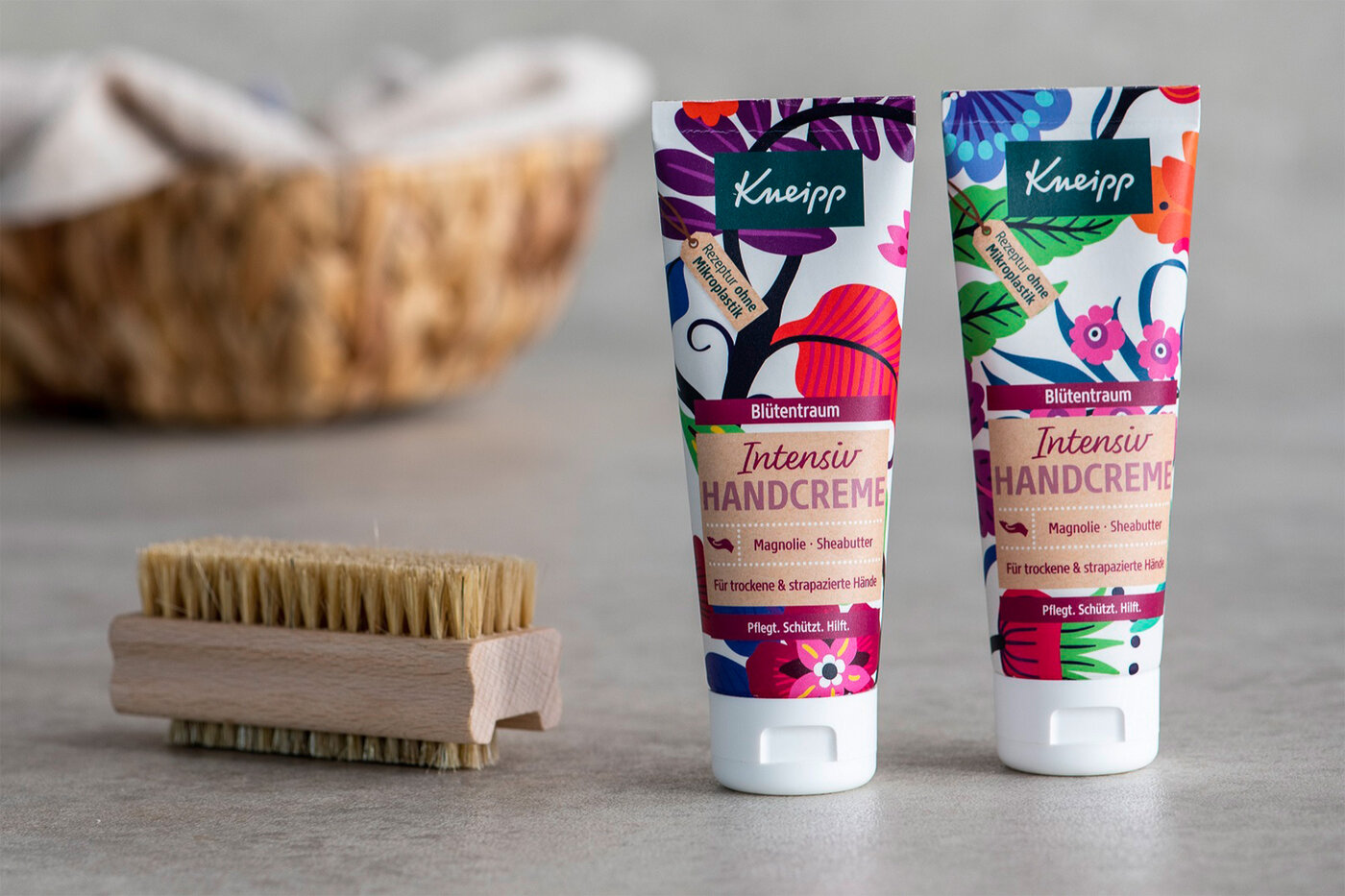 Zwei Handcreme-Tuben mit einer Hand-Bürste daneben 