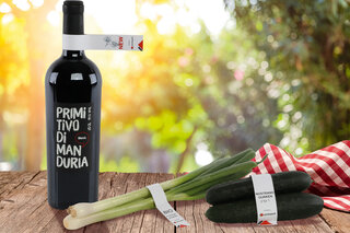 Une bouteille de vin, des oignons de printemps et des concombres avec des étiquettes LoopTack.