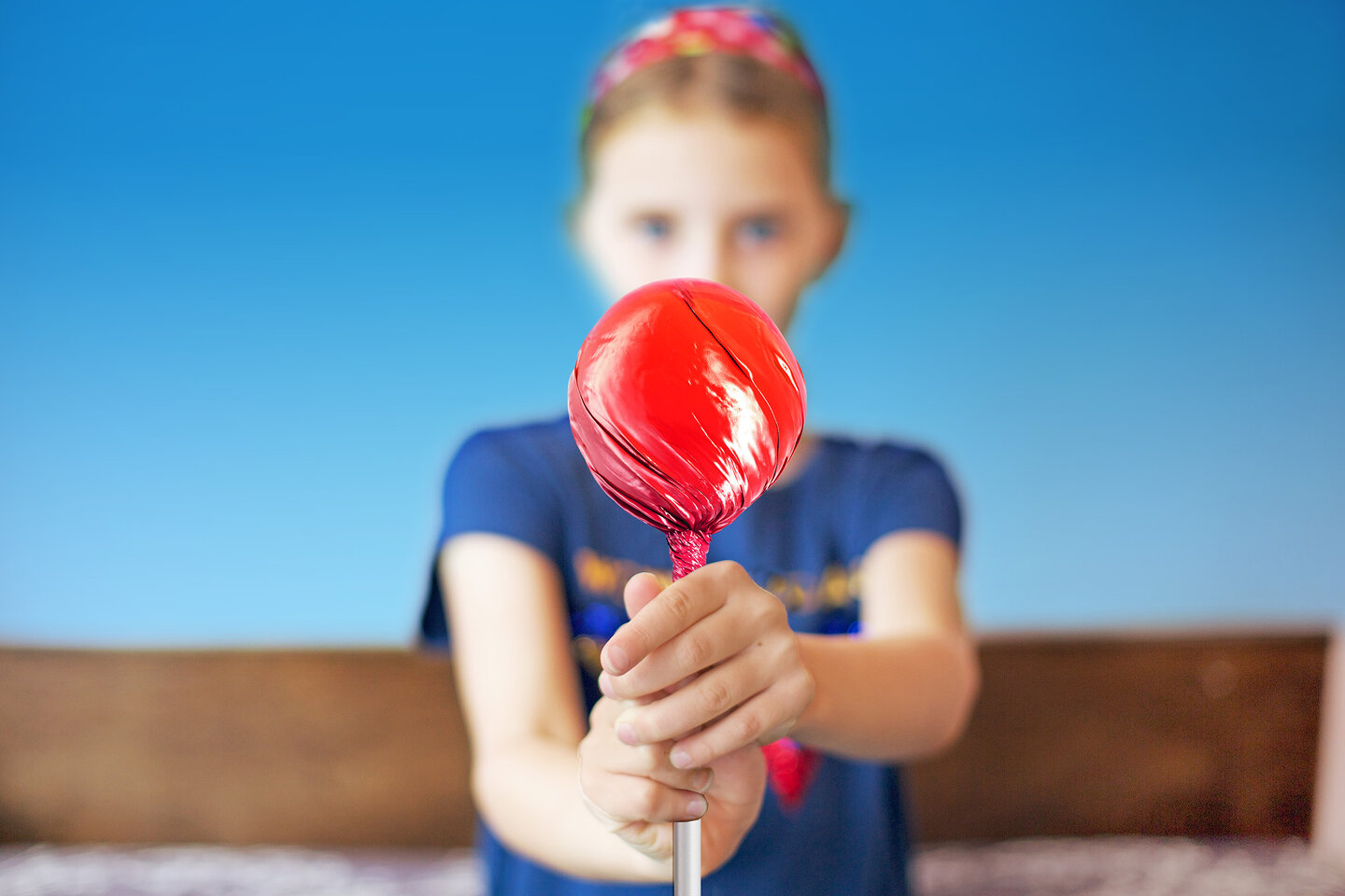 Une fille qui soulève une sucette rouge. 