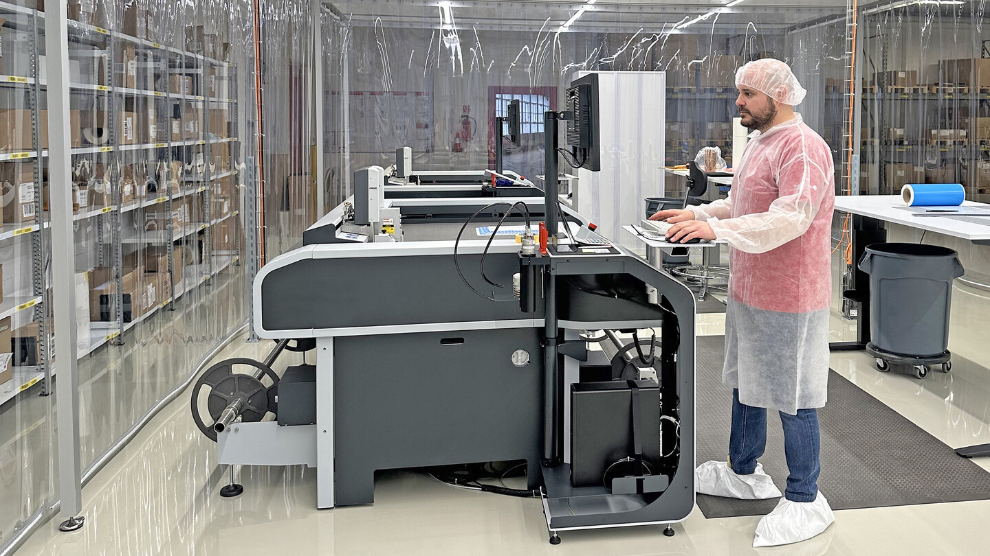 Un homme en vêtements de protection blancs fait fonctionner une machine dans une salle blanche.