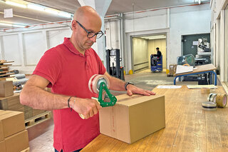 L'employé ferme un carton avec un ruban pour paquets durable en PP recyclé.