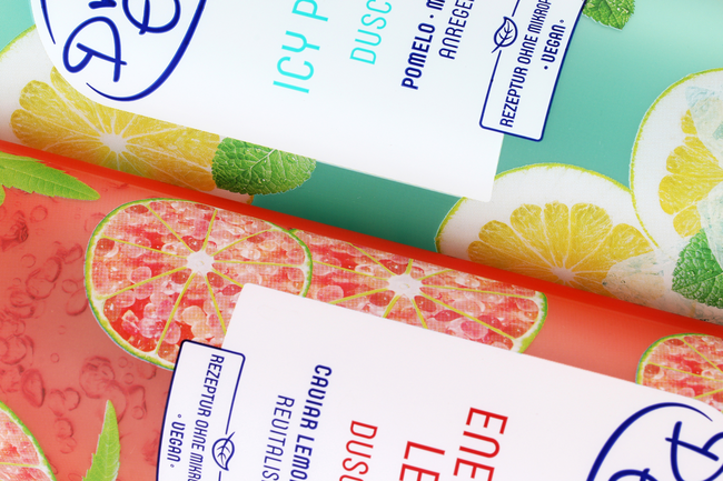 Nahaufnahme von zwei Tubenlaminat-Verpackungen in Grün und Rot mit Zitrusmotiven und Veredelungselementen