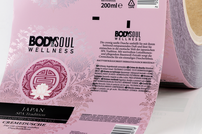 Rosa Tubenlaminat-Folie auf einer Rolle mit Produktinformationen, floralem Muster und Glanzeffekt