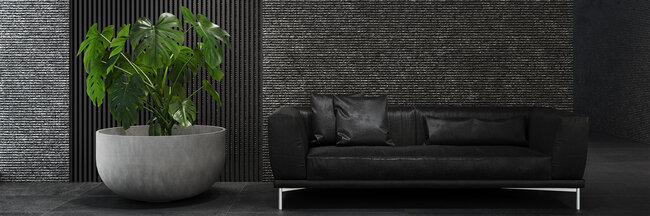 Jardinière ronde couleur béton de la marque Cosapots avec une plante Monstera devant un mur sombre