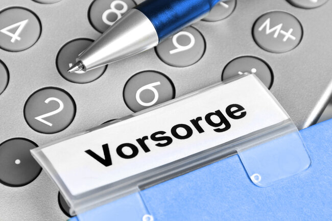 Classeur étiqueté «Prévoyance» posé sur une calculatrice avec un stylo.