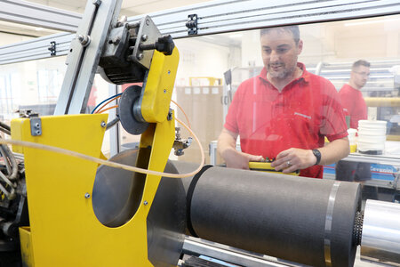 Ein Mitarbeiter bedient eine Rollenschneidmaschine zum Schneiden von nicht klebenden Bändern