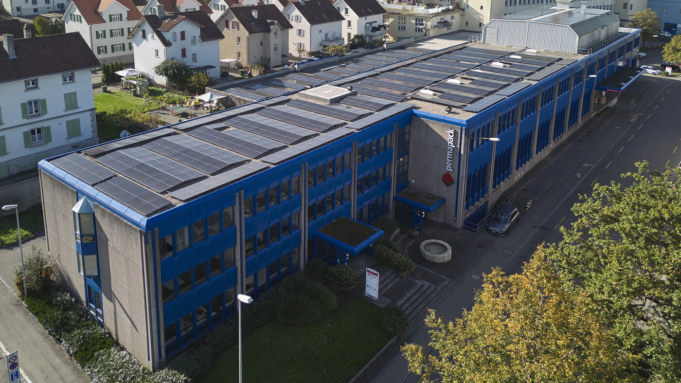 Das blaue Permapack-Gebäude mit Photovoltaik-Anlage auf dem Dach. 