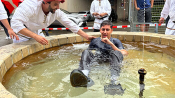 Un homme assis dans un puits rempli d'eau, derrière lui quatre hommes