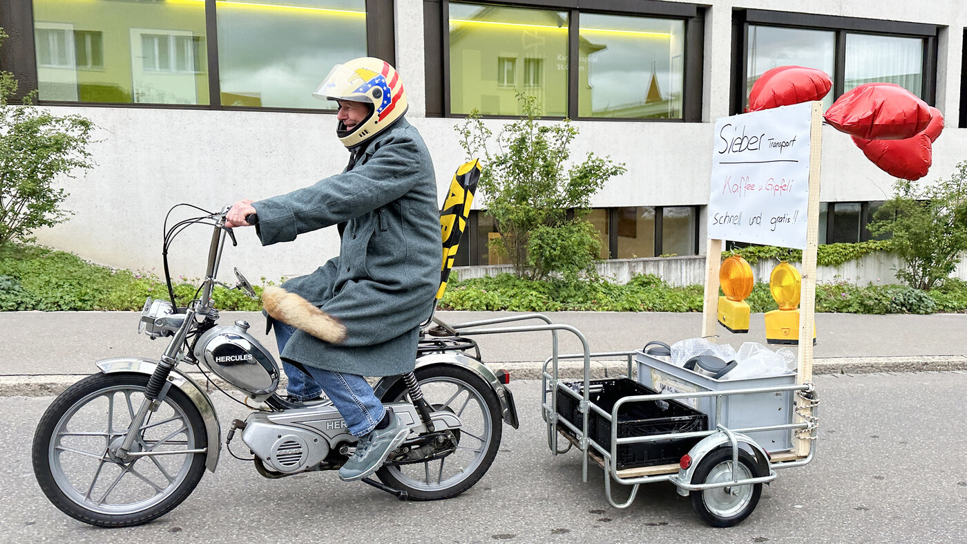 Peter Sieber sur le Töfli avec café et croissants dans la remorque. 