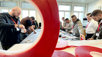 Atelier de collage: plusieurs participants sont debout autour d'une table de travail.